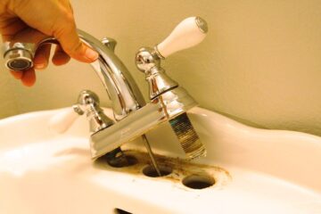 The image shows a man remove old bathroom sink faucet.