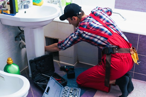 The image show a plumber fixing smelly bathroom sink.