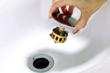 The image shows a lady who unscrew bathroom sink drain.