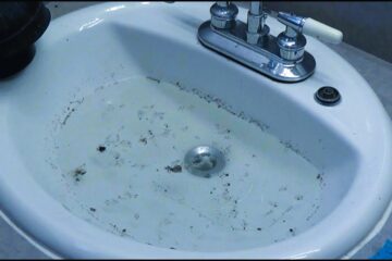 The image shows a clogged bathroom sink.