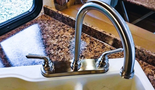 The image shows a loose kitchen sink faucet.