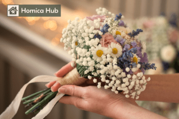 The image shows a woman's hand holding a small wedding bouquet which is full of small mix flowers.